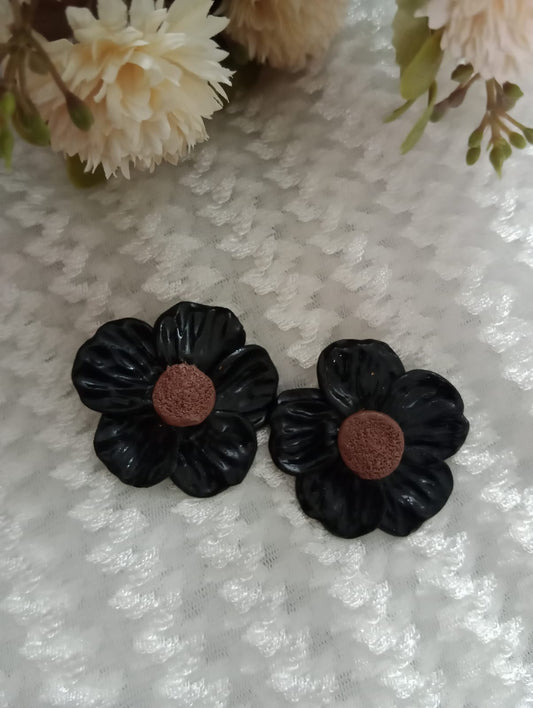 "Elegant Black Flower Earrings on Textured Fabric"